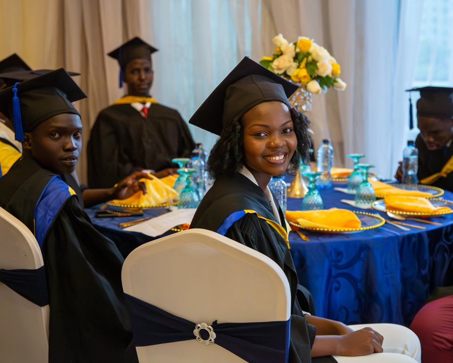 Alexia Umugwaneza ’23 and fellow graduates sitting at a table decorated with blue and yellow items 