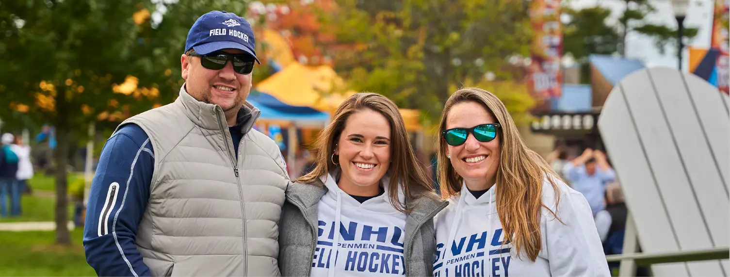 Daughter and parents smiling together in SNHU field hockey support merchandise