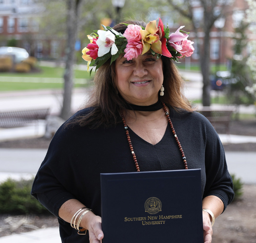 woman wearing a flower crown and holding her college degree