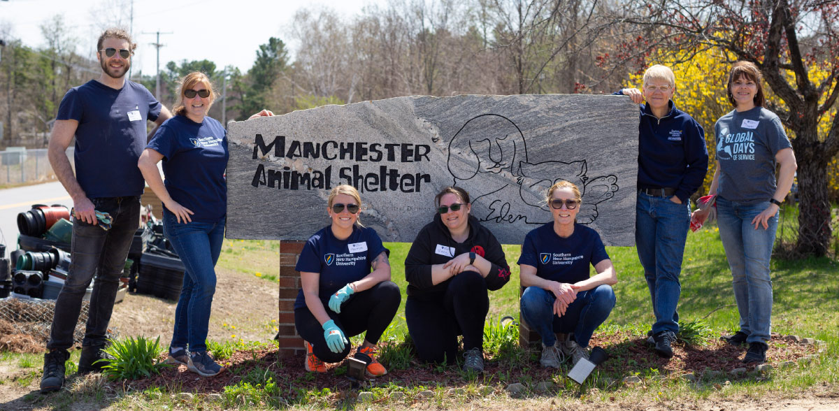 alumni, students, staff, and faculty posing in front of Manchester Animal Shelter sign