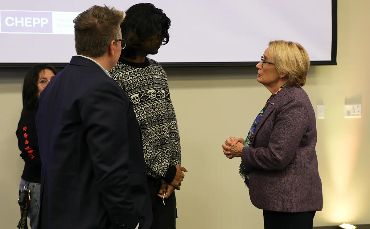 Landscape orientation close-up indoor photograph view of Senator Maggie Hassan meeting with a student panelist as they talk amongst each other while there are two other individuals nearby them listening in on the conversation