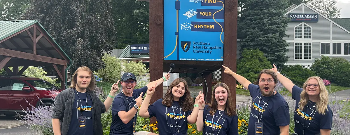 interns enthusiastically pointing at a Southern New Hampshire University sign