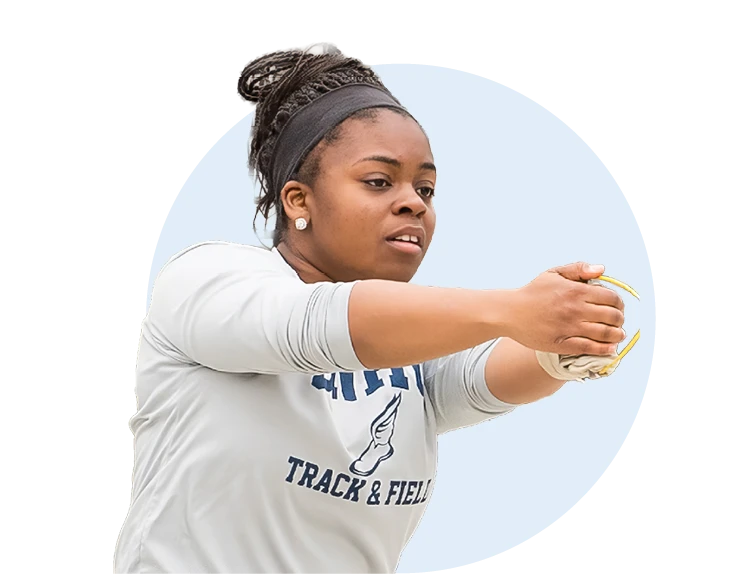 SNHU track and field athlete Ashley prepares to throw a shot put, extending her arms forward during competition.